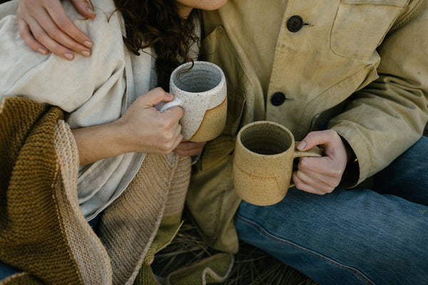 two friends outside cozied up with a mug