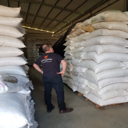 image of a man stood with loads of differant bags fillled with coffee beans 