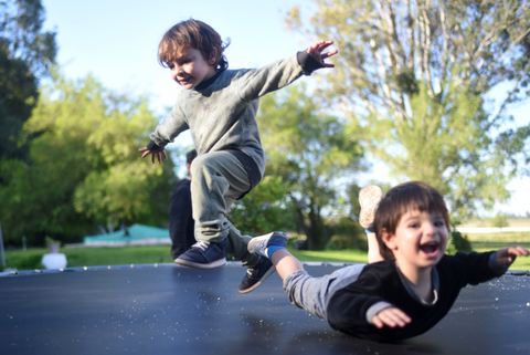 two kids jumping on a trampoline one of the outdoor activities to keep toddlers and kids busy