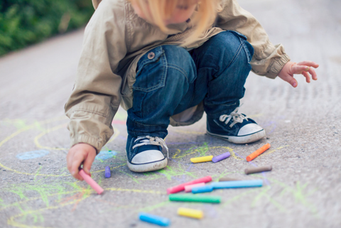 kid doing  sidewalk with chalk one of the outdoor activities to keep toddlers and kids busy