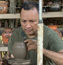 Miguel throwing pottery on a hand spun wheel