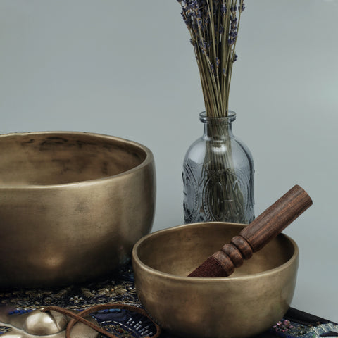 On the table are a brass bowl, a brass mortar and a glass jar. Lavender in a glass bottle.