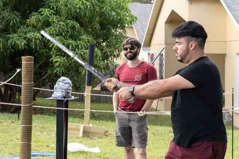 Instructor watches over student cutting tatami with sharp longsword with clay cutting stand in background