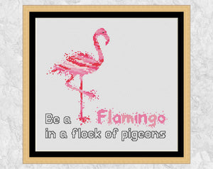 Cross stitch pattern PDF of a watercolour effect flamingo, with the words 'Be a Flamingo in a flock of pigeons'. Shown with frame.