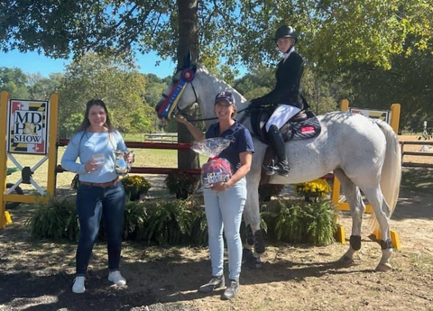 Taylor Kamataris, winner of the high children's/adult jumper championship at the Maryland Horse and Pony Show, shown with her ribbon, trophy, and Pinsnickety horse show number pin prizes