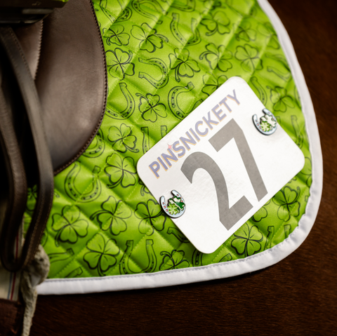 pinsnickety horseshoe horse show number pins on a green saddle pad with clovers