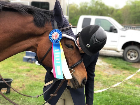 a rider kissing an ottb with a champion ribbon