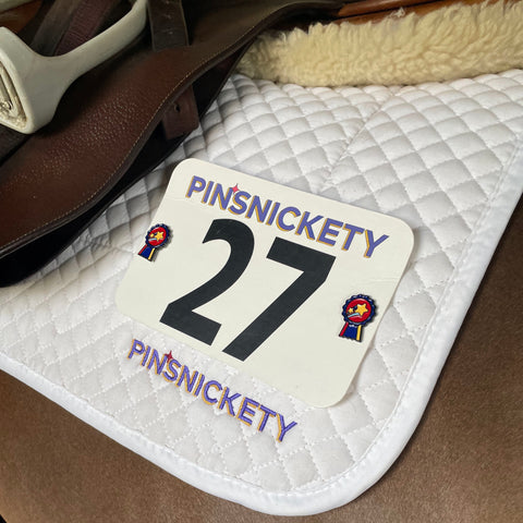 pinsnickety champion horse show number pin and charm on a saddle pad