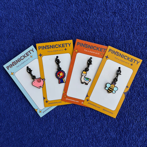 pinsnickety flying pig, champion, drama llama, and queen bee braid or bridle horse show charms on a blue background