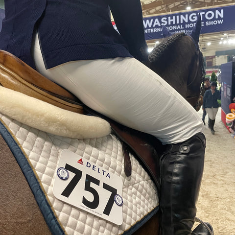 Pinsnickety custom washington international horse show number pins on a saddle pad at the ingate.