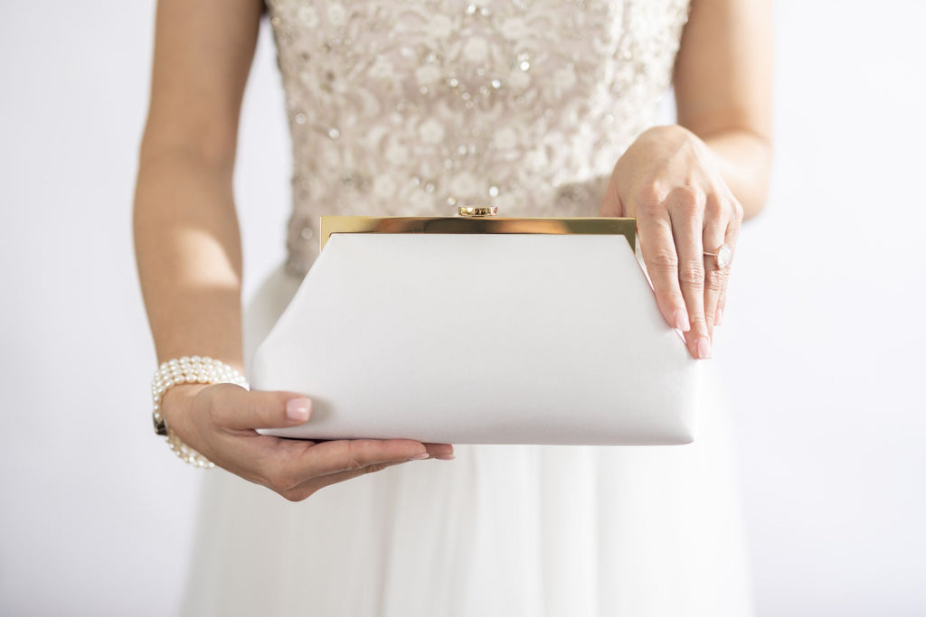 Bride holding rosa clutch in ivroy.