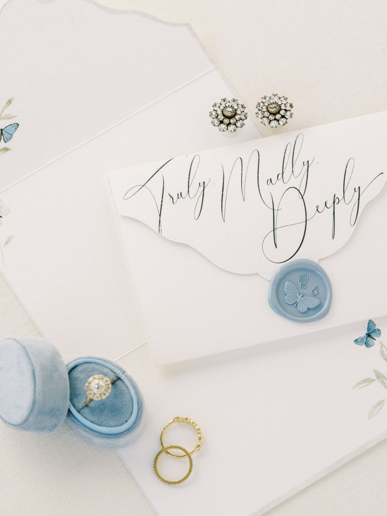 Bridal stationery set styled with rings and blue ring box.