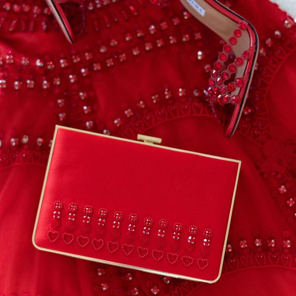 Custom designer handbag in red satin with custom red beating against a red dress and red shoes.