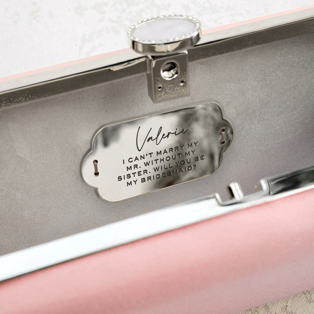 Personalized designer purse in pink satin open with a custom engraving plaque in silver sewn into the inside of the clutch.
