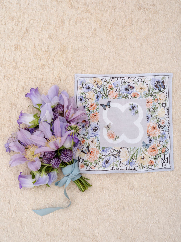 Bridal handkerchief laid out next to wedding floral bouquet.
