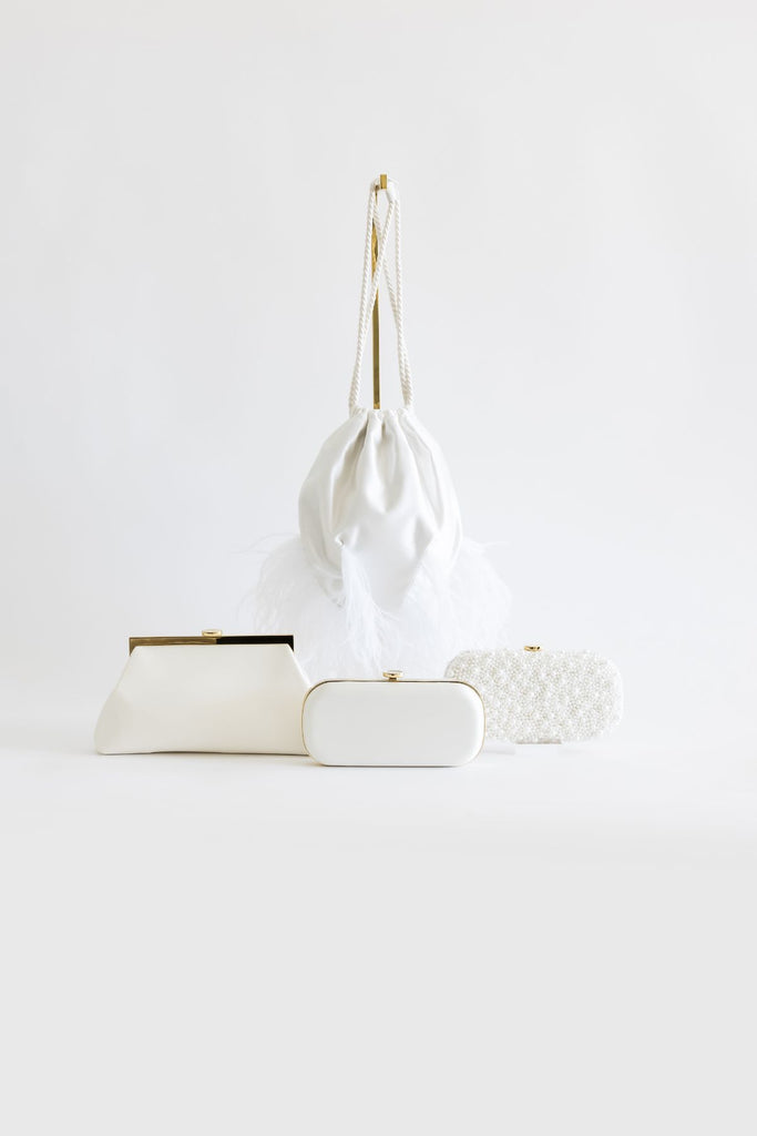The Sarah Drawstring bag pictured above three clutches, in order the Rosa Clutch, the Bella Clutch in Ivory, and the True Love Pearl Clutch.