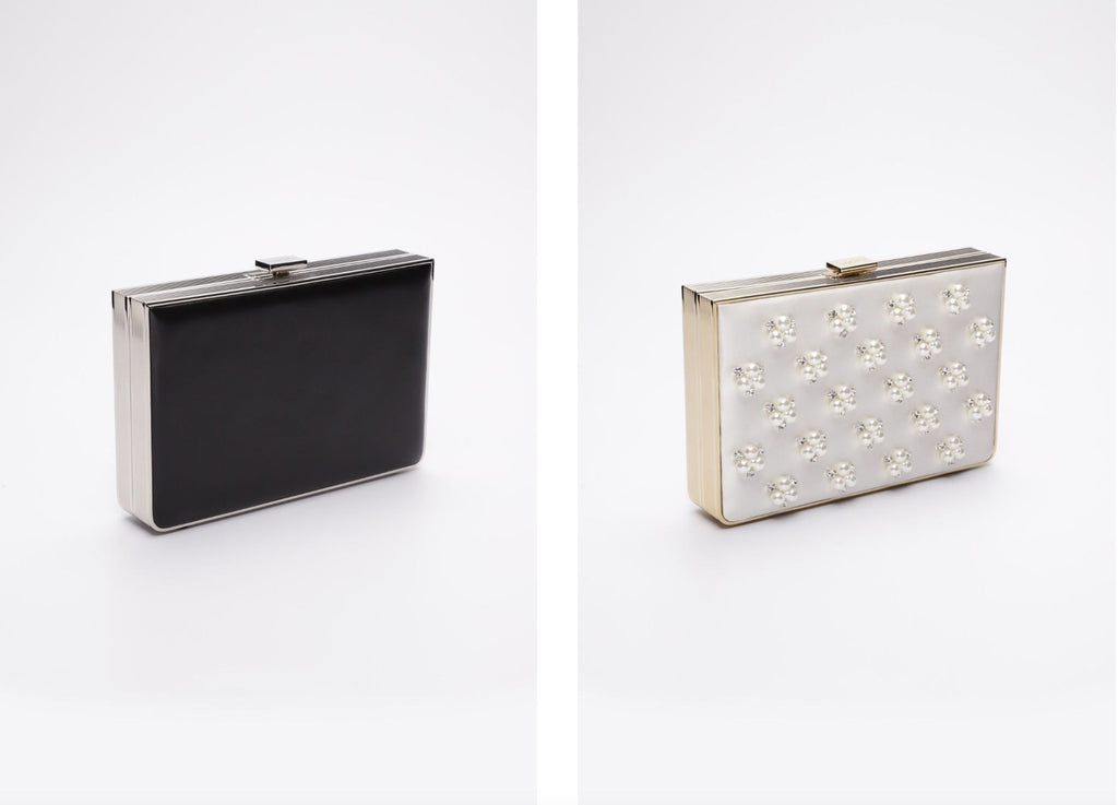 Two Venezia Clutches side-by-side. The Venezia clutch on the left is in black leather, the Venezia clutch on the right is the white satin beaded pearl clutch.