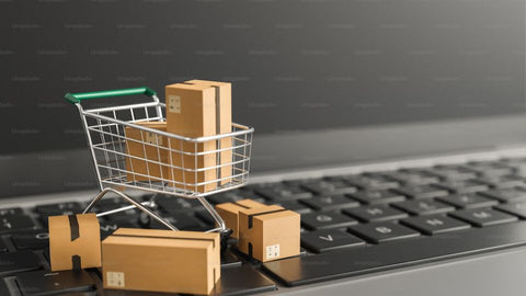 A shopping cart on laptop keyboard with a bunch of boxes in it