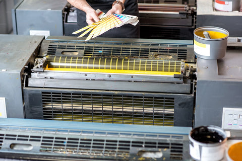 man standing with a printing machine with yellow paints