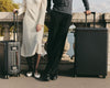 Man and women lean on Parisian bridge holding two stylish suitcases