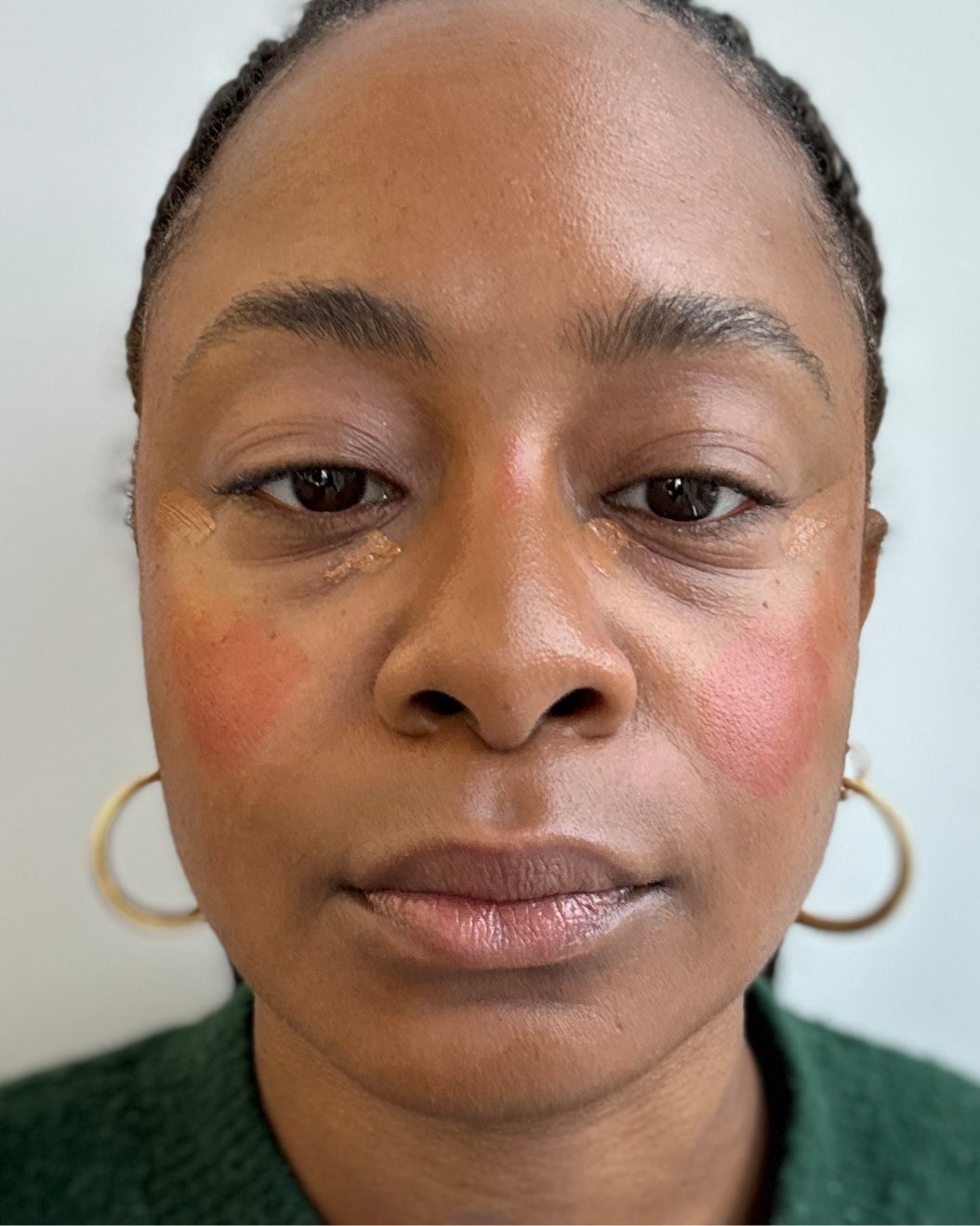 Woman with ombre blush and under eye concealer before it's blended on a white background