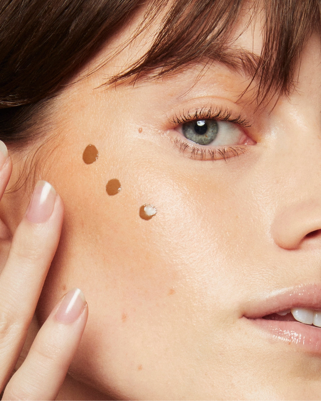 Close-up portrait of a model with three dots of Milk Makeup Bionic Bronzer along her cheekbones