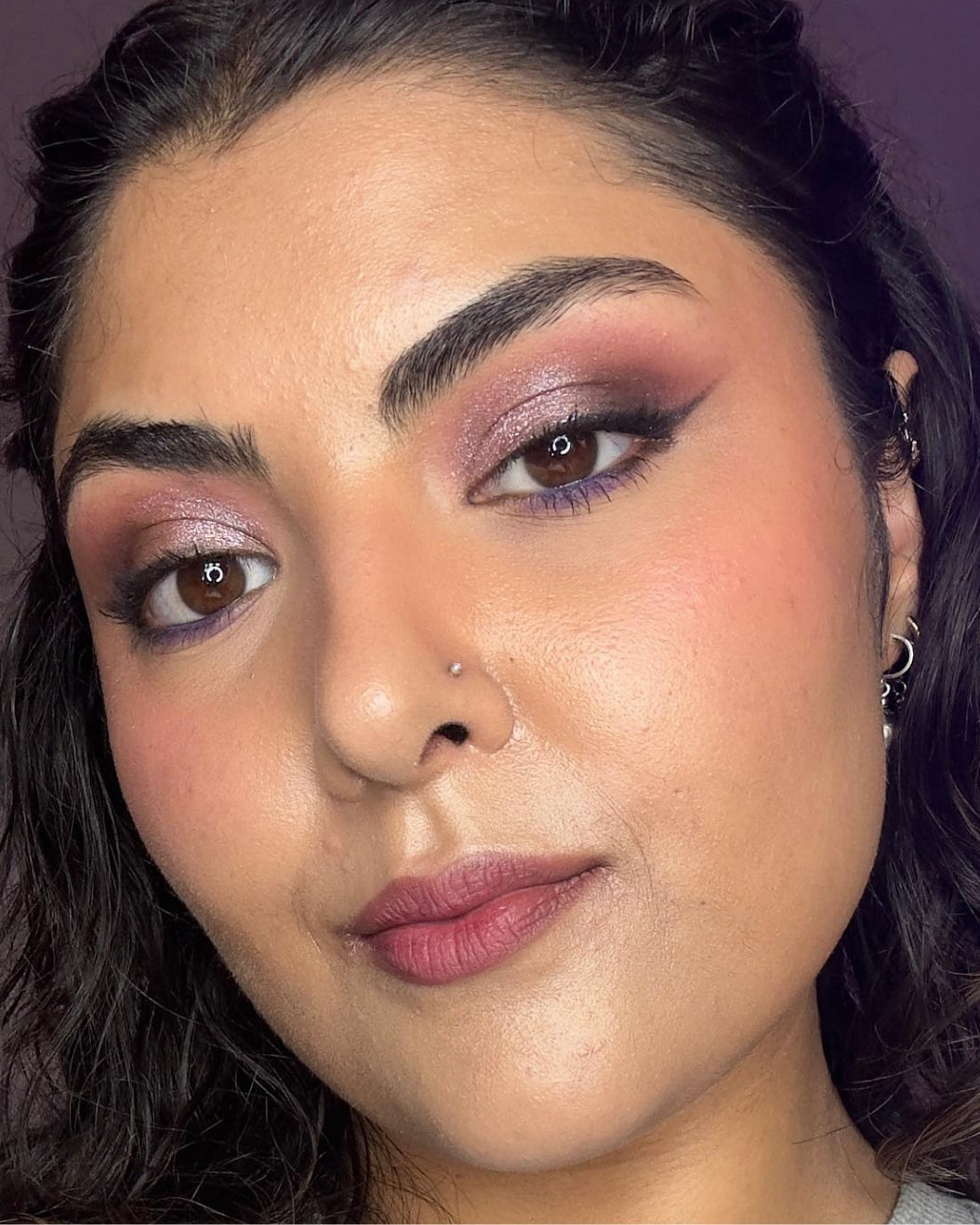 Model wears dusty rose and purple eye makeup for holiday makeup inspiration