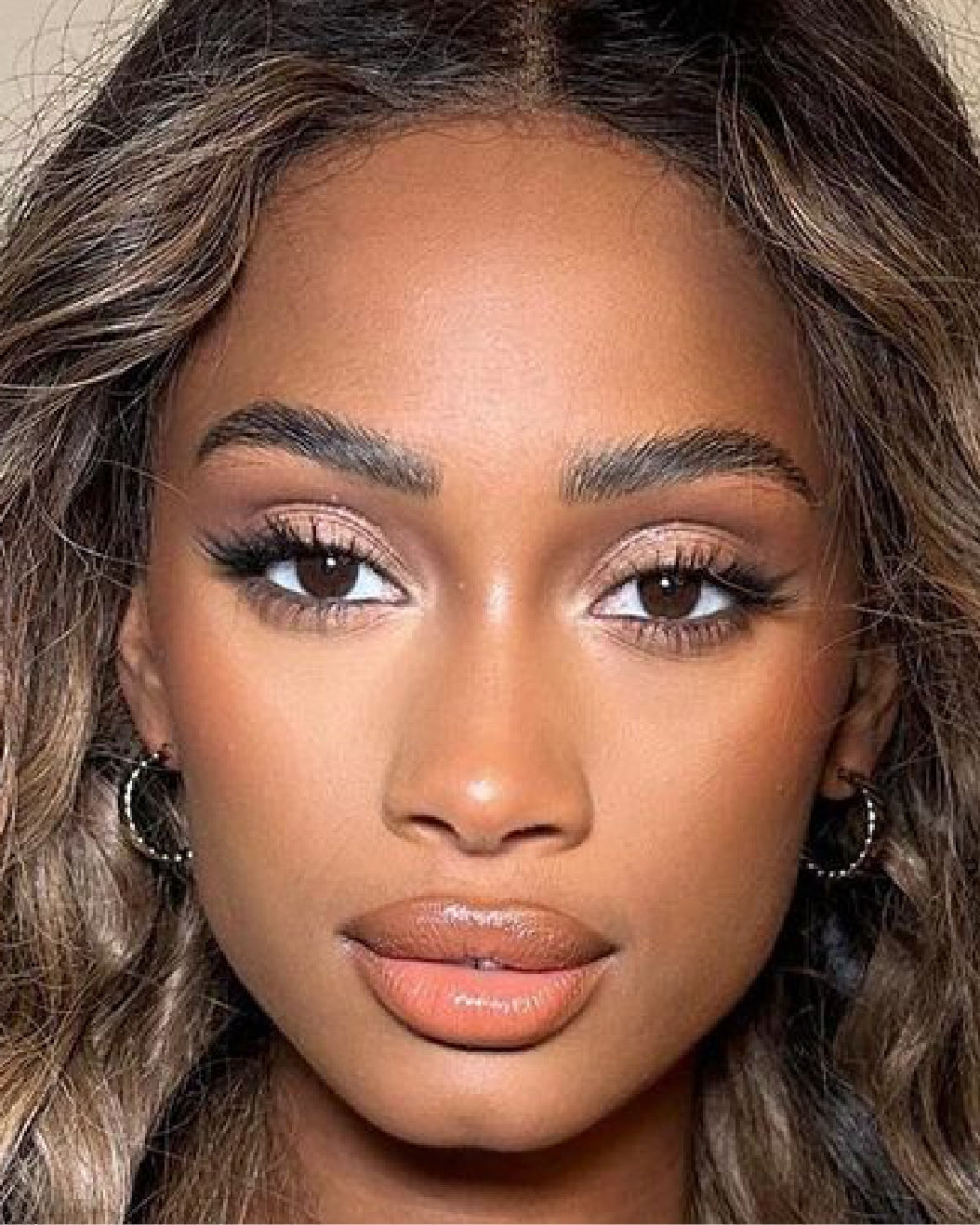 Stunning brown-skinned model wears neutral soft glam makeup for holiday makeup inspiration