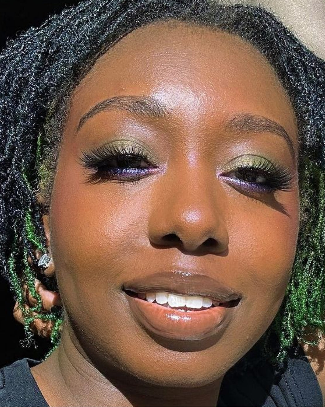 Model wears green and purple shimmery eyeshadow for holiday makeup inspiration