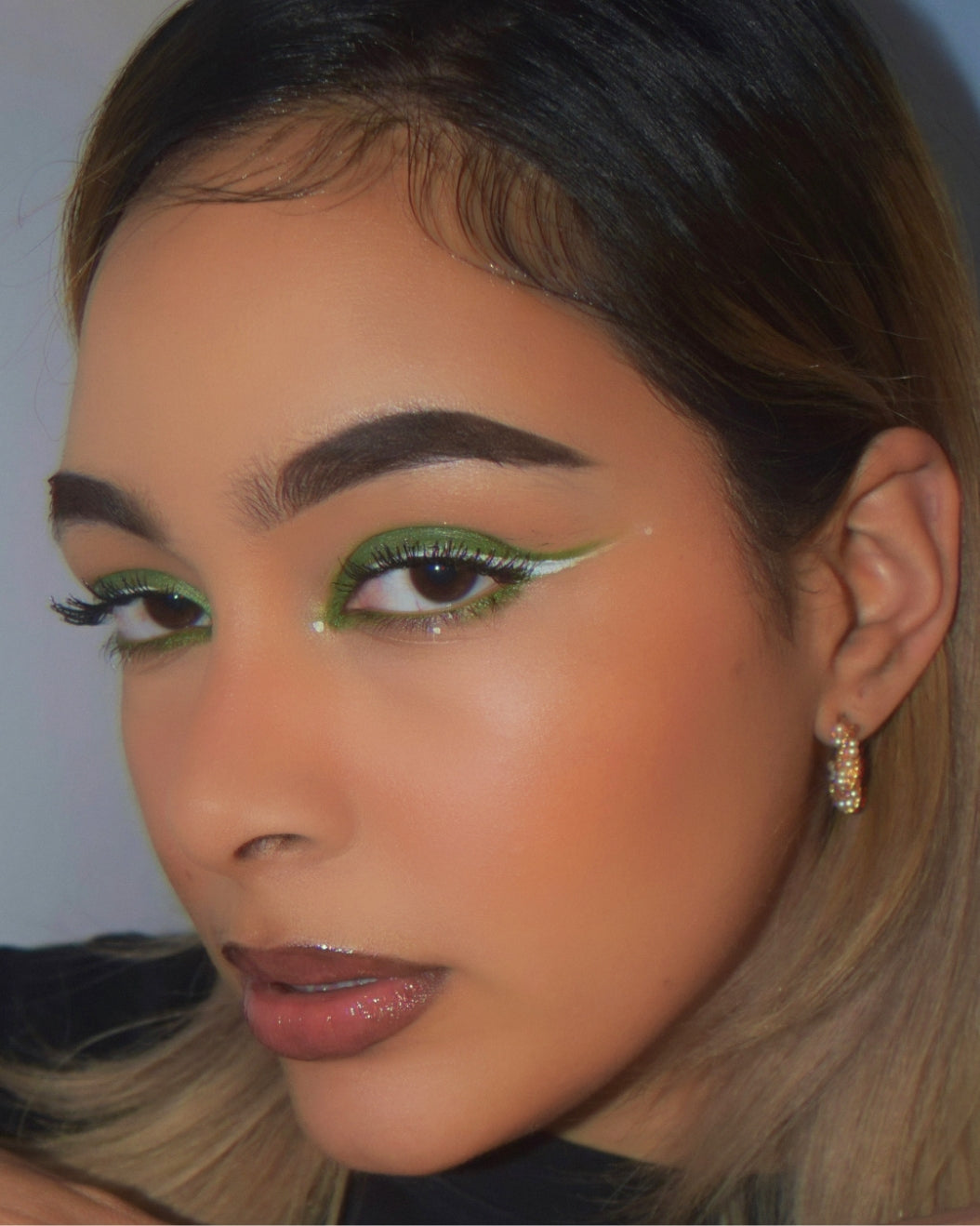 Makeup artist wears a matcha latte-inspired makeup look with vibrant green eyeshadow and light green winged eyeliner