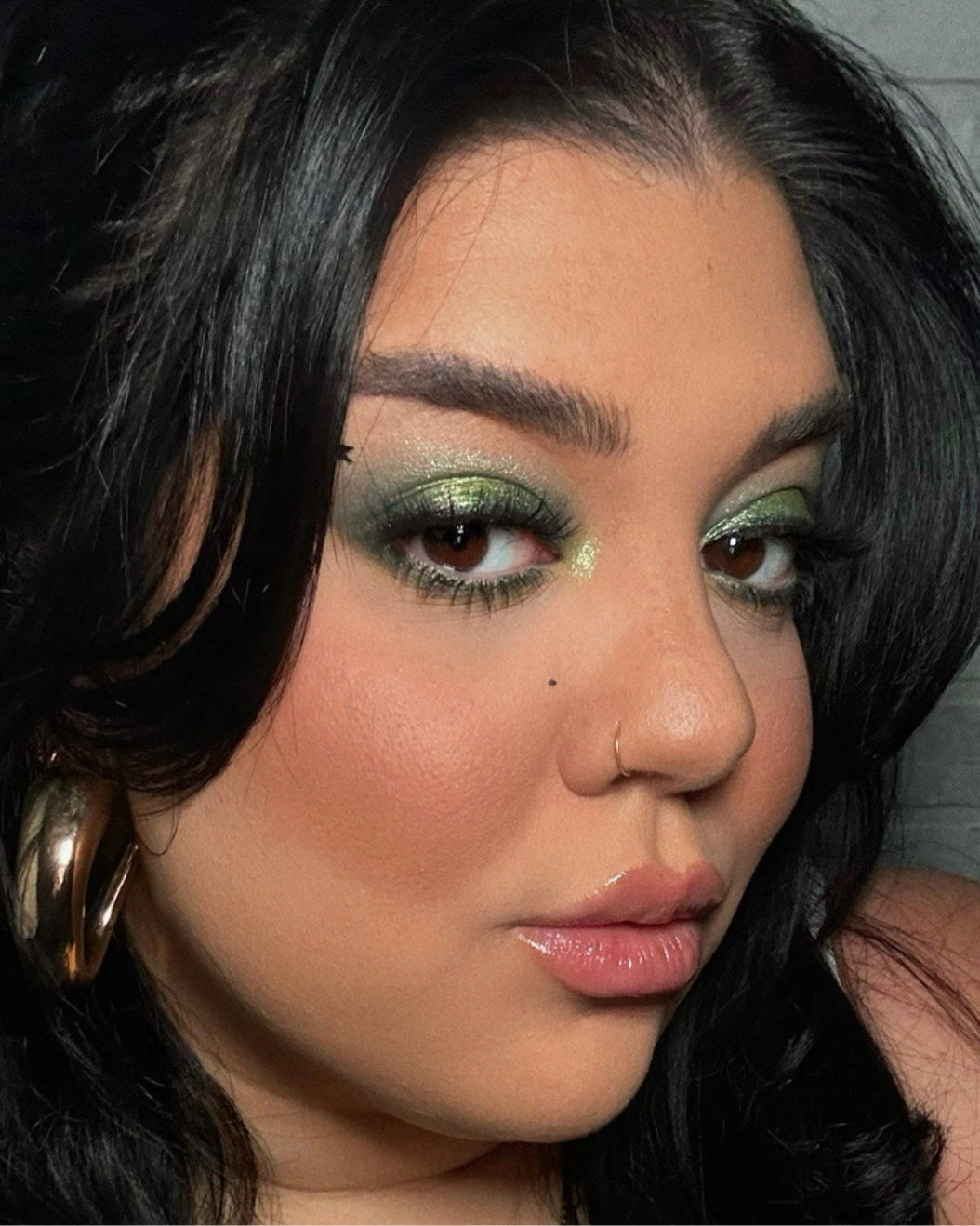 Makeup artist wears a matcha latte-inspired makeup look with shimmery green eyeshadow and dusty rose nude lips