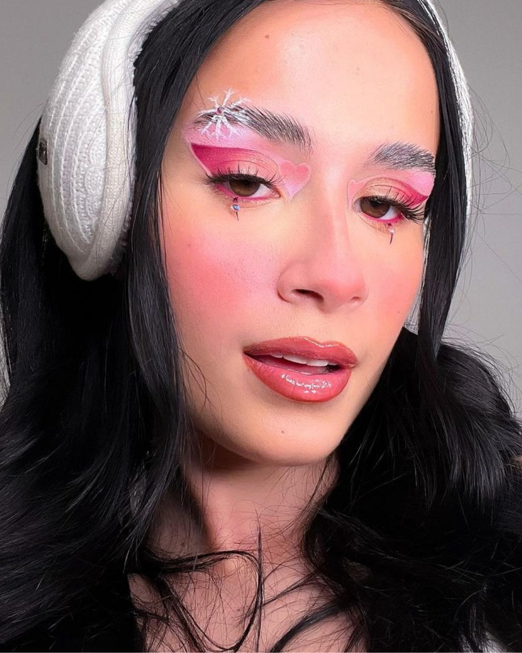 Portrait of a woman wearing pink snowflake eye makeup to use as holiday makeup inspiration
