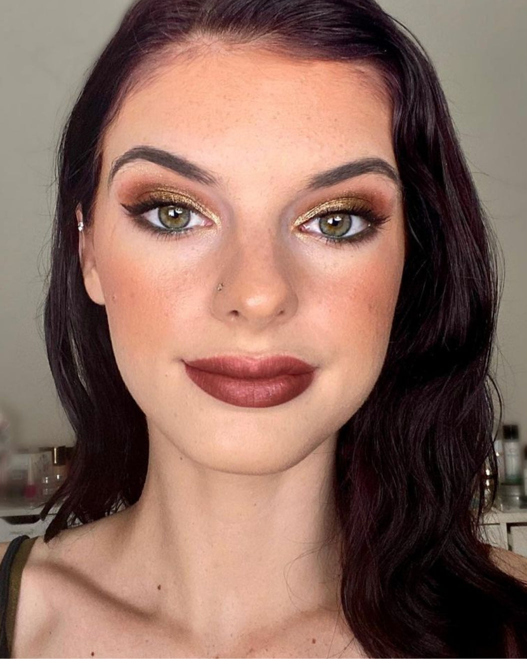 Portrait of a person wearing Gold eyeshadow with brown lipstick for holiday makeup inspiration