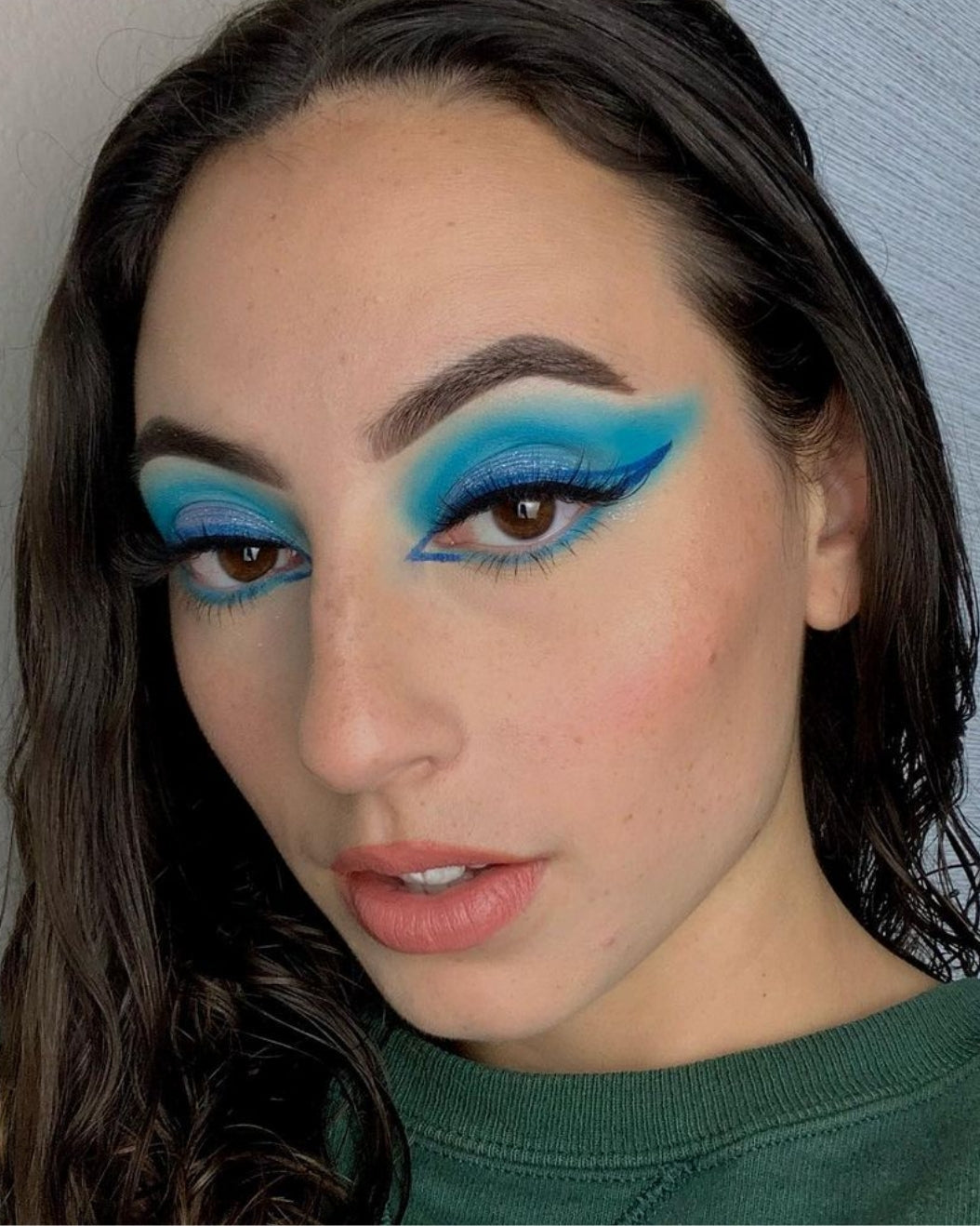 Portrait of a woman with bold blue makeup to use for holiday makeup inspiration