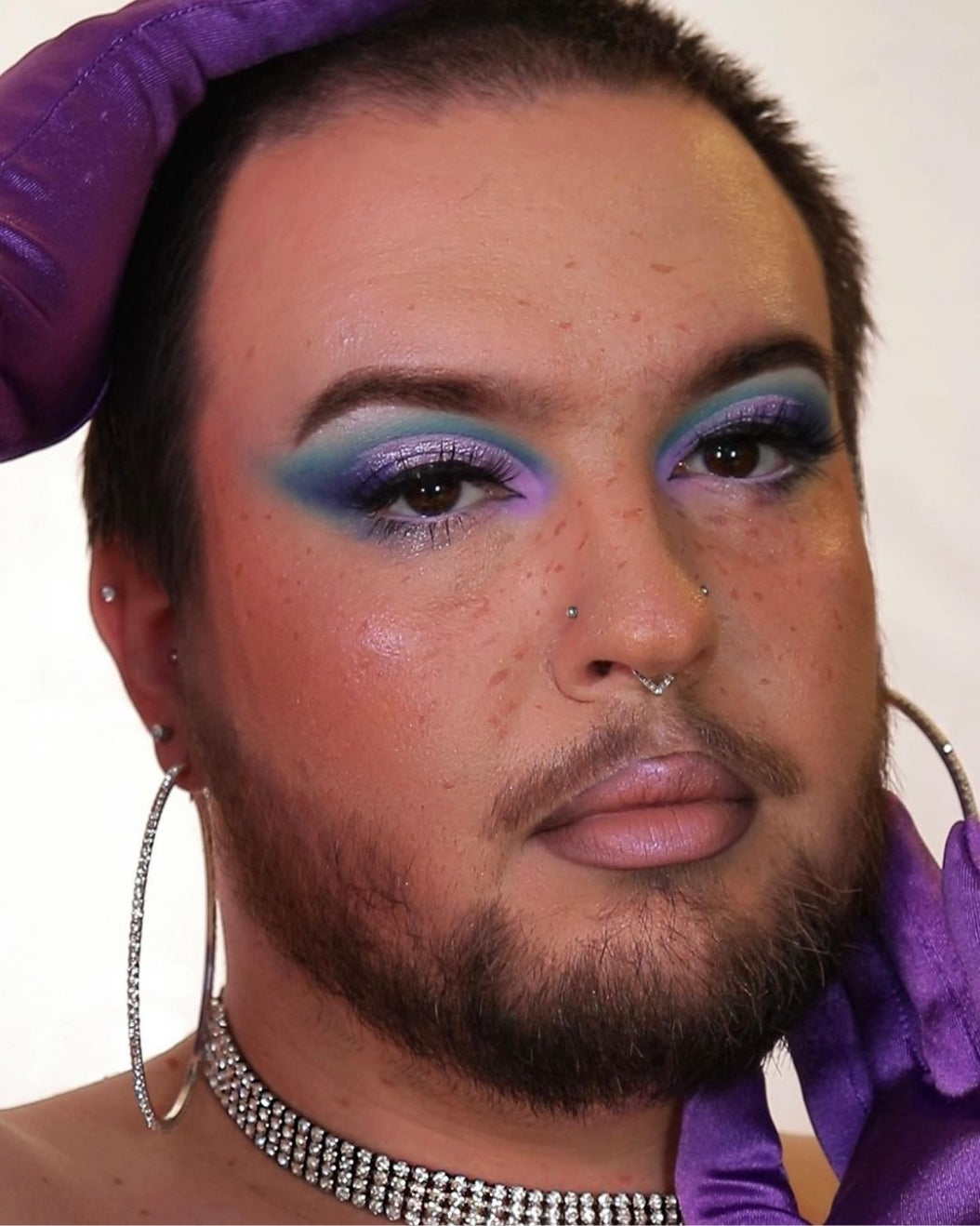 Portrait of a person with blue and purple cut crease eye makeup to use as holiday makeup inspiration