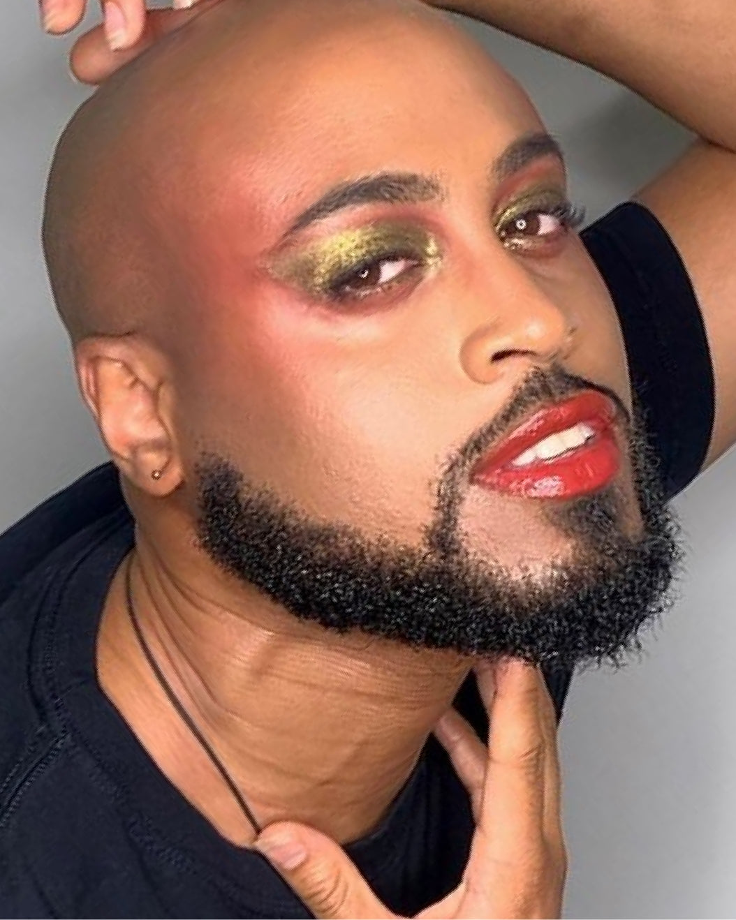 Portrait of a bearded man wearing gold and red holiday makeup