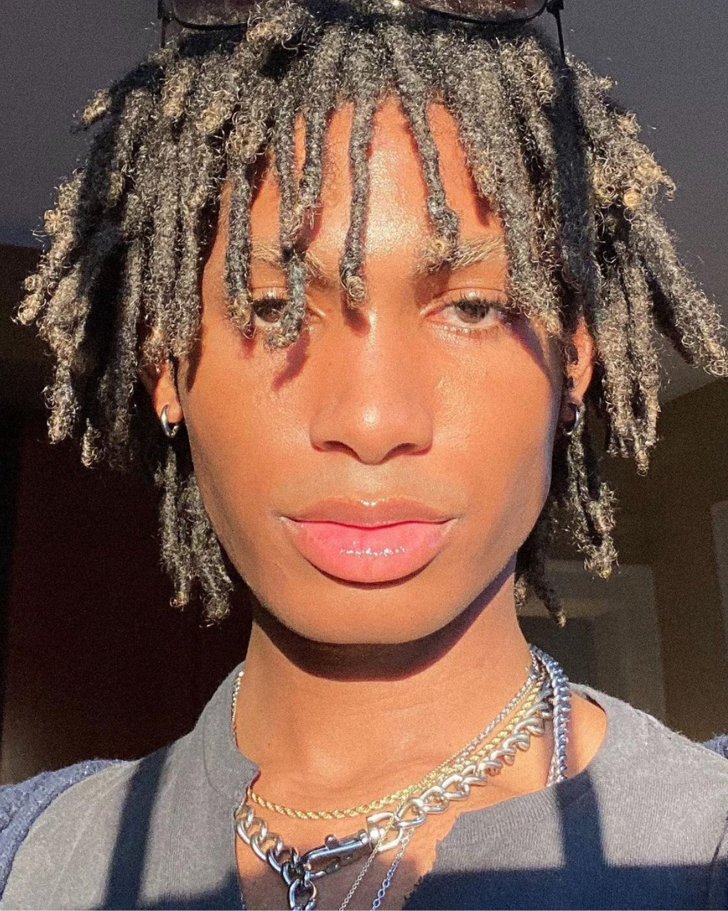 Portrait of a person with dewy skin and short locs to use as holiday makeup inspiration