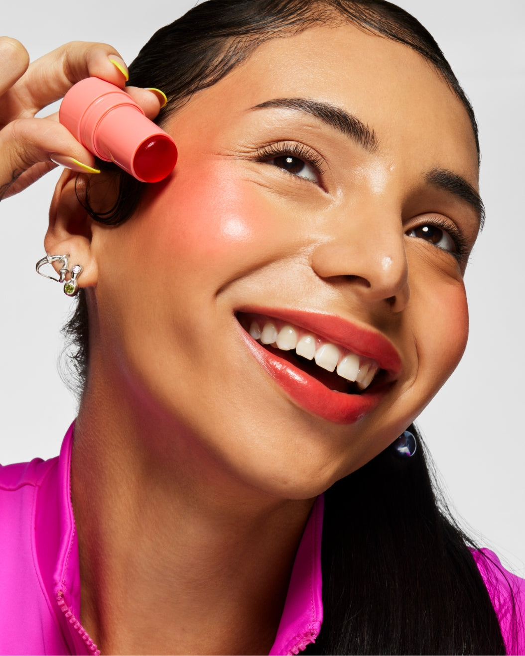 Model holds a stick of Milk Makeup Cooling Water Jelly Tint against their cheek on a white background