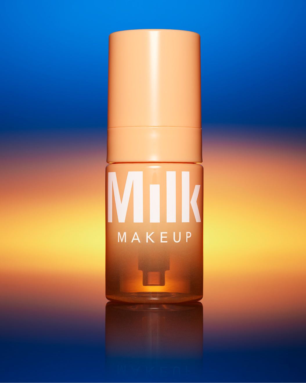 Bottle of Milk Makeup Cloud Glow Priming Foam on a blue-orange gradient background