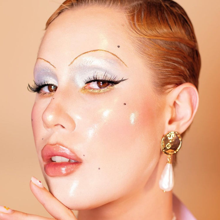 : Creator wears a makeup look inspired by Pat McGrath's Maison Margiela Spring 2024 Couture show on a beige background