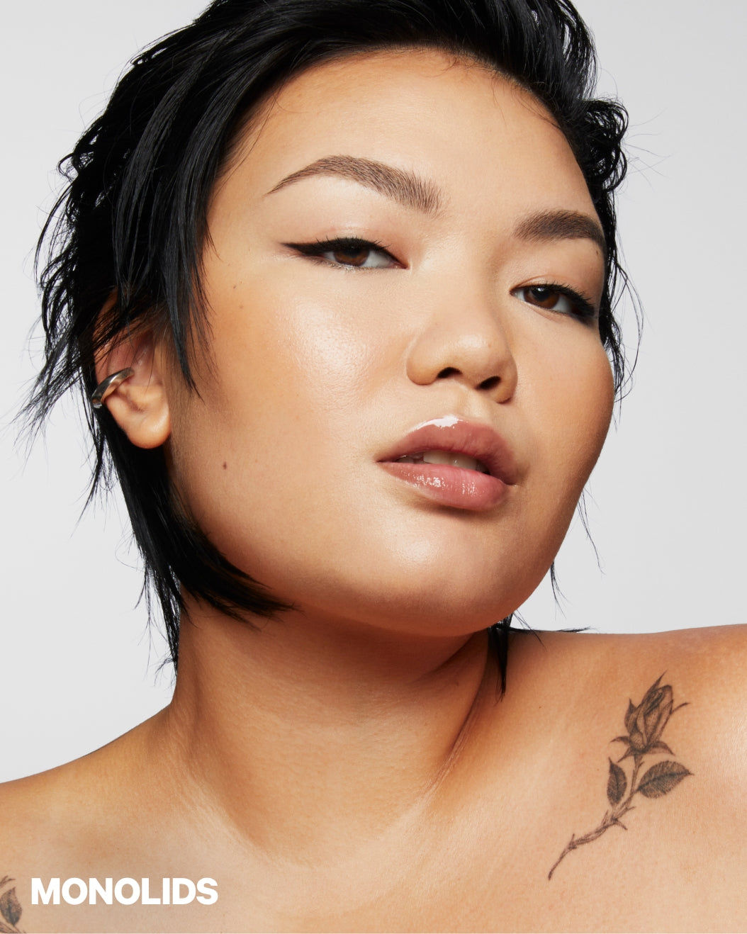 Model with monolids wears winged eyeliner on a white background
