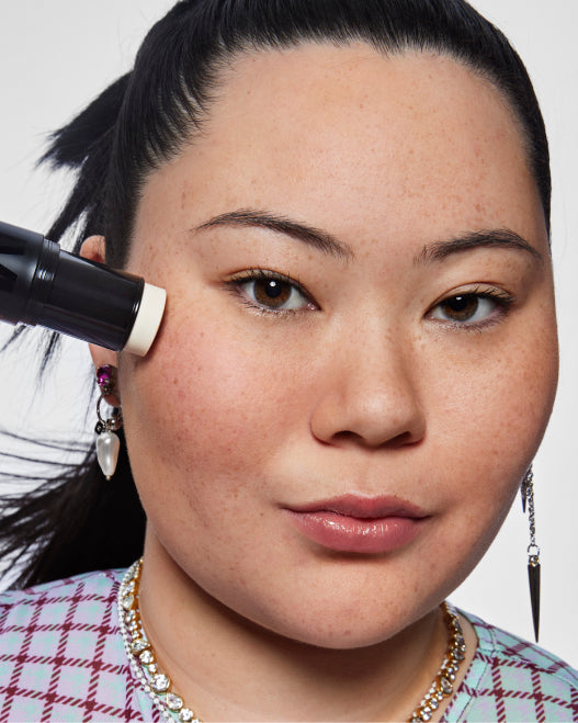 Model applies Milk Makeup Pore Eclipse Matte Blur Stick to their cheek against a white background