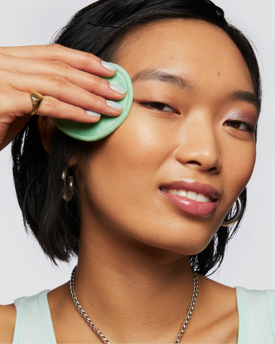 Model removes makeup with Hydro Ungrip Reuseable Pads on a white background