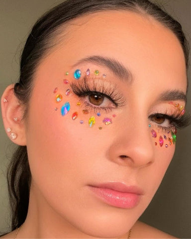 Model wears makeup with multicolored gems arranged around her eyes