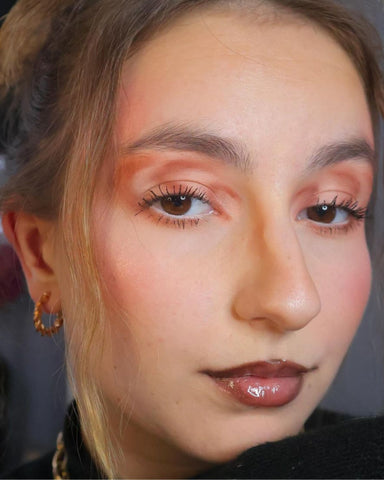 Selfie of a model with graphic eyeshadow on a gray background
