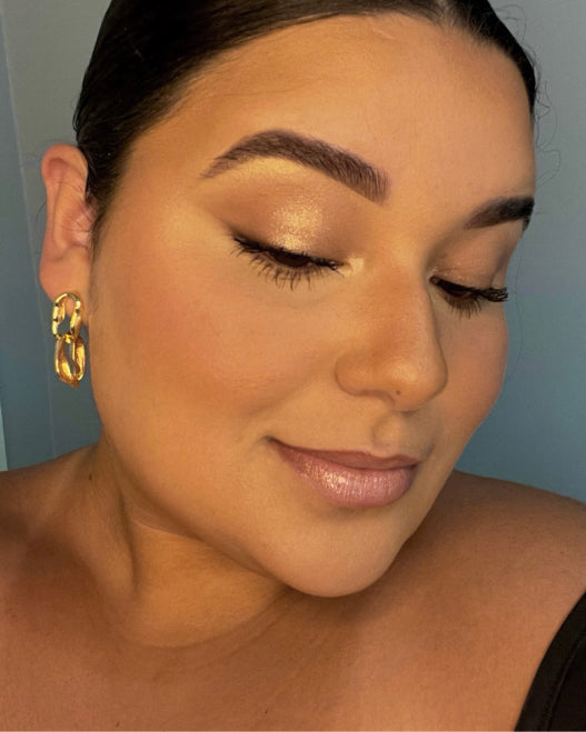 Model wears a wedding guest makeup look with reflectgive gold highlighter