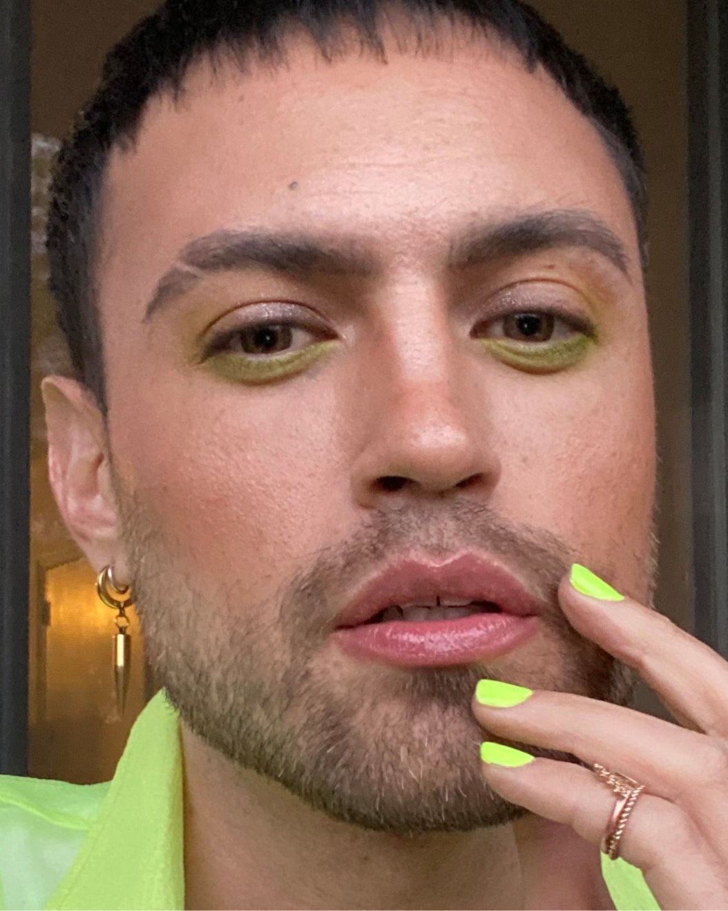 Selfie of a person with lime green eye makeup in a matching lime green outfit.