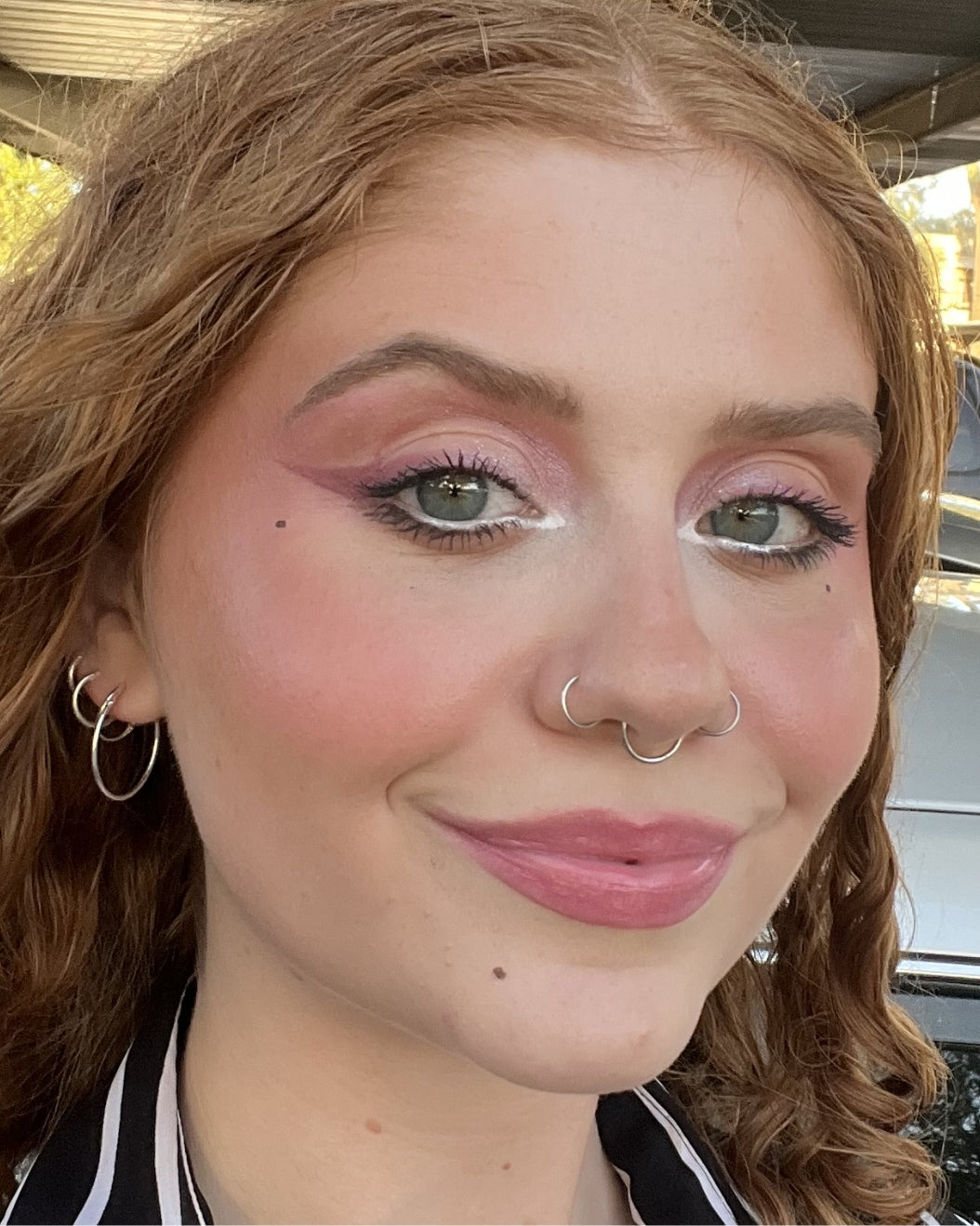 Makeup artist wears a back-to-school makeup look featuring cat-eye liner in a mauve shade.