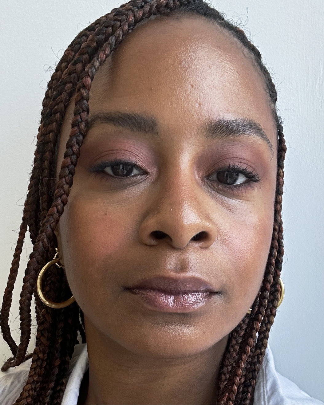 Woman wears a neutral brick-colored eyeshadow look paired with Milk Makeup Odyssey Lip Oil Gloss in Voyage