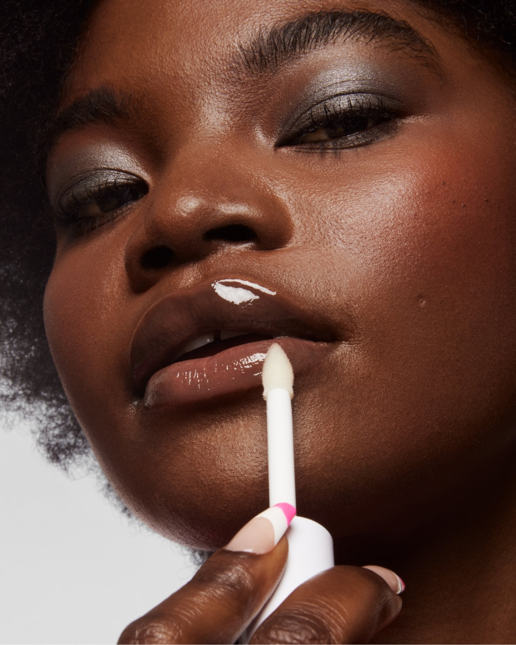 Model applies Milk Makeup Odyssey Lip Oil Gloss in Journey against a white background